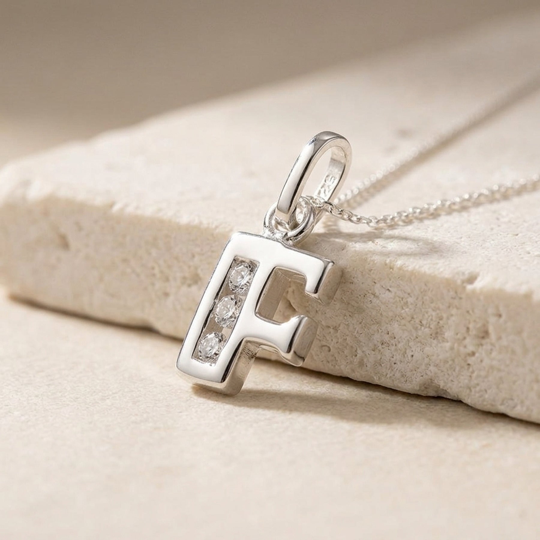 Anhänger Buchstabe F glänzend mit Zirkonia – 925er Silber, 8 × 7 mm – Detailansicht des Anhängers vor neutralem Hintergrund