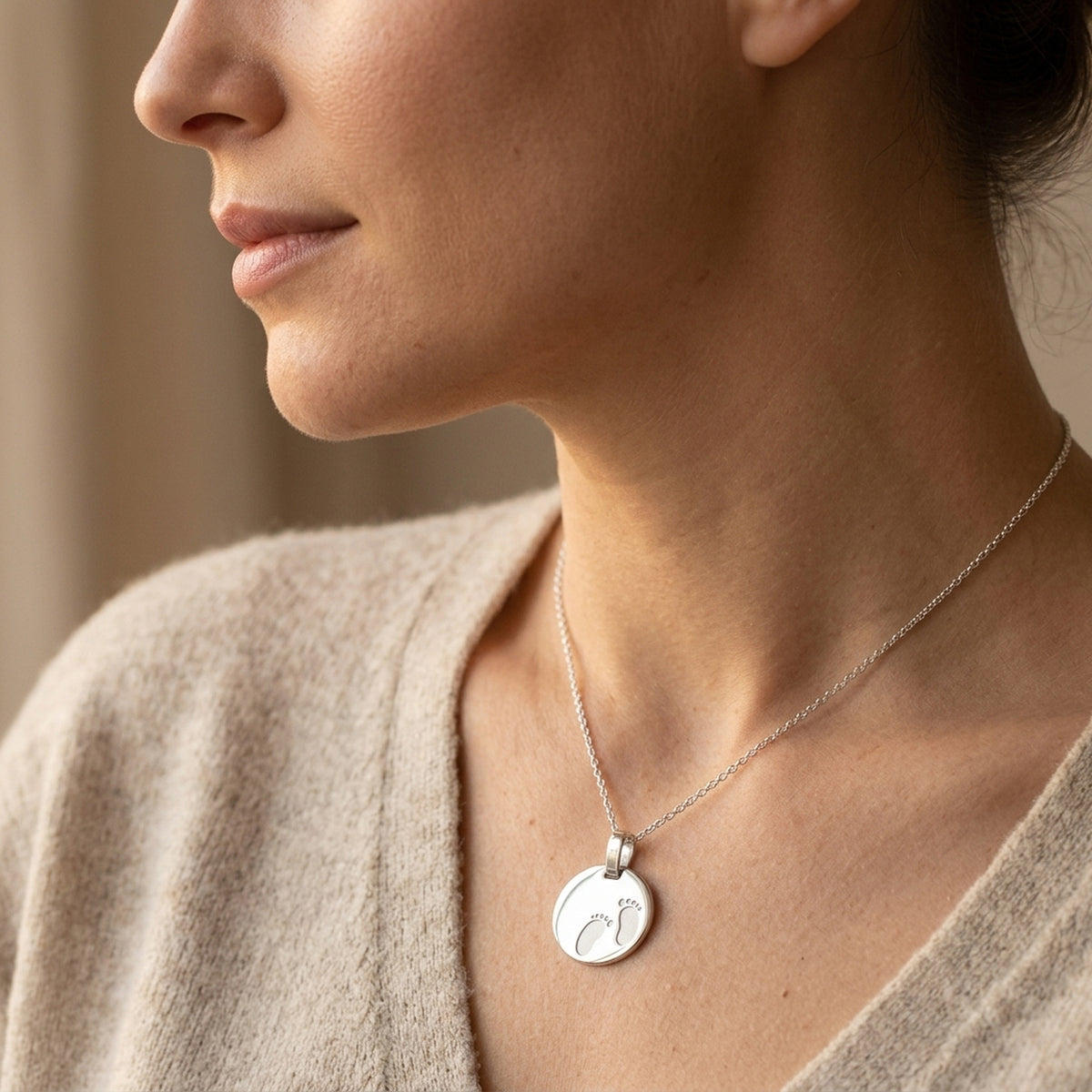 Anhänger Gravuranhänger zur Geburt Füße glänzend-matt – 925er Silber, 21 × 17 mm – an einer feinen Kette getragen, zweite Lifestyle-Aufnahme in anderer Perspektive