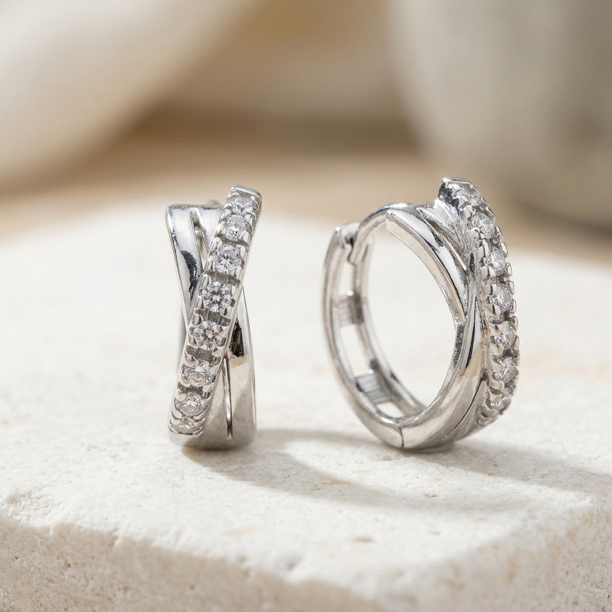 Gekreuzte Creolen mit Zirkonia, rhodiniert – 925er Silber, 12,5 × 5 mm – Detailansicht des Ohrschmucks vor neutralem Hintergrund
