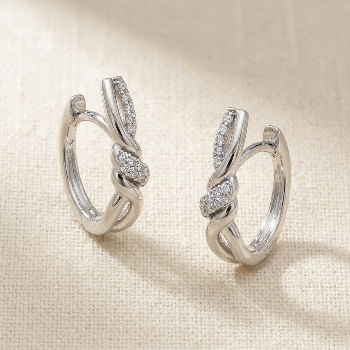 Überkreuzte Creolen mit Zirkonia, glänzend – 925er Silber, 17 × 4 mm – Detailansicht des Ohrschmucks vor neutralem Hintergrund