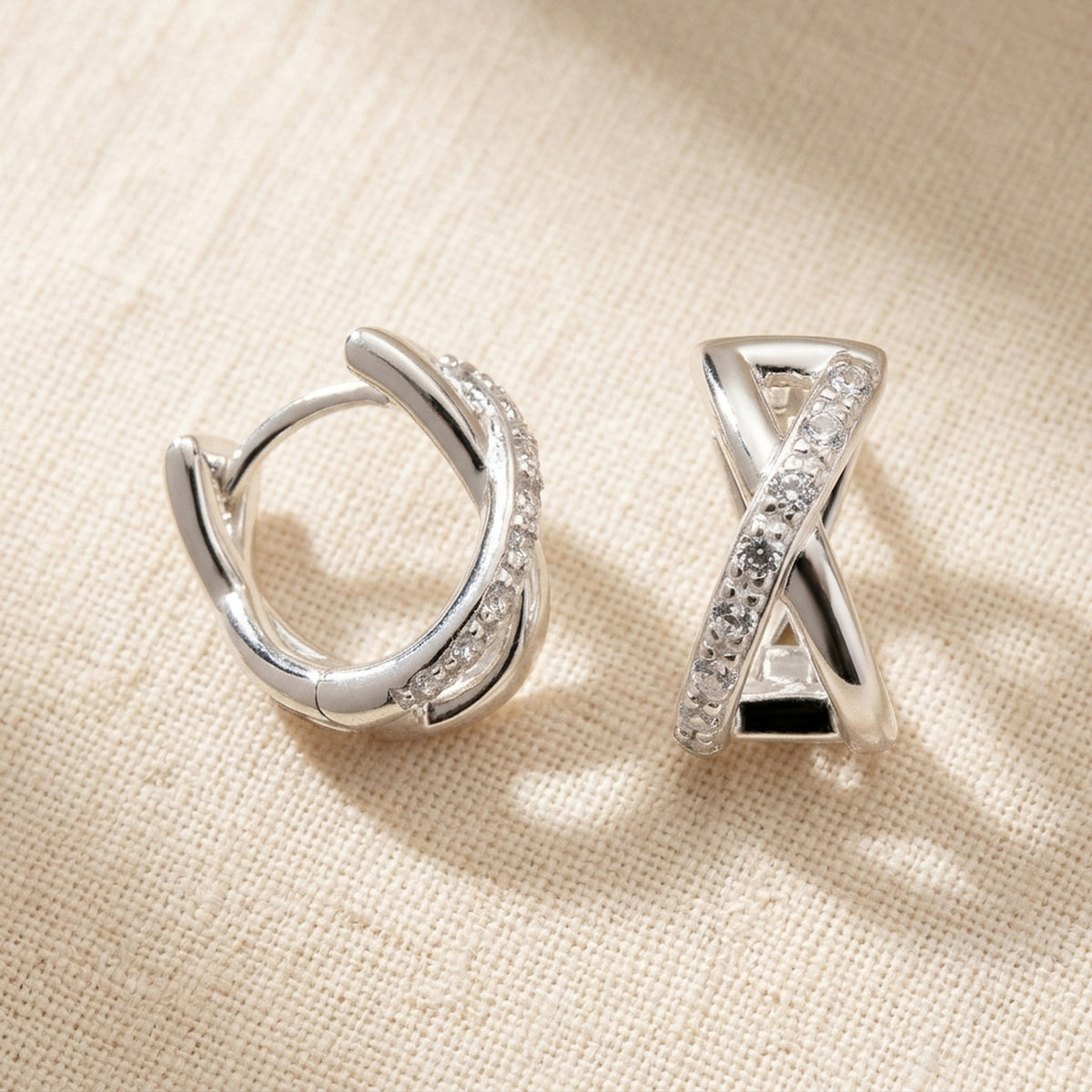Überkreuzte Creolen mit Zirkonia – 925er Silber, 11 × 6 mm – Detailansicht des Ohrschmucks vor neutralem Hintergrund