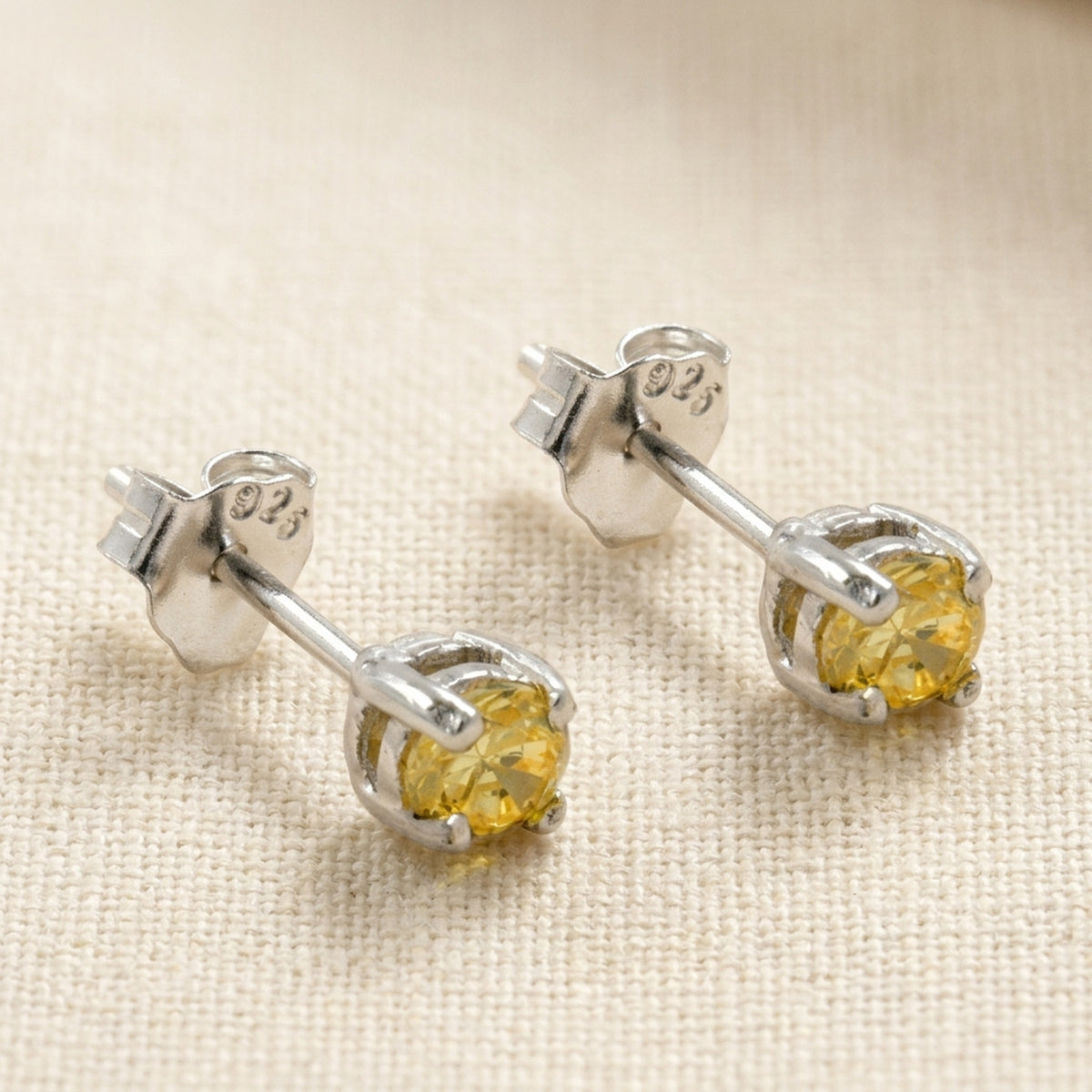Ohrstecker mit citringelbem Glasstein, rhodiniert – 925er Silber, 3 × 3 mm – Detailansicht des Ohrschmucks vor neutralem Hintergrund