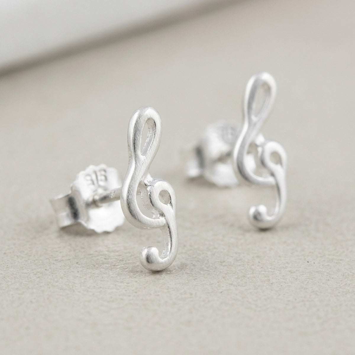 Ohrstecker Notenschlüssel – 925er Silber, 9 × 3 mm – Detailansicht des Ohrschmucks vor neutralem Hintergrund