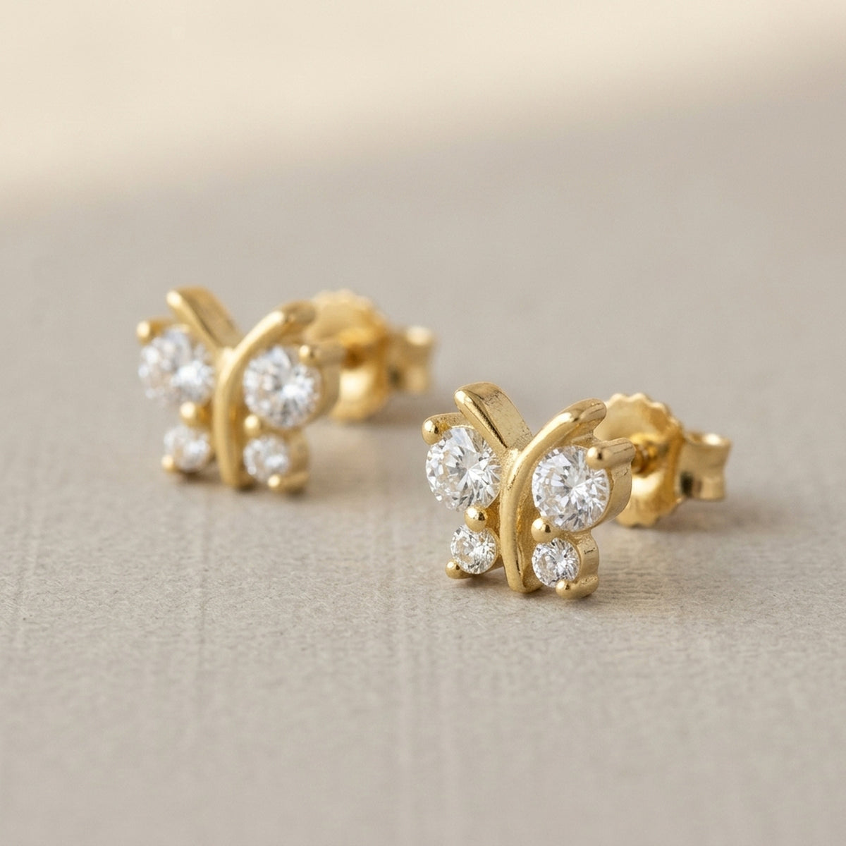 Ohrstecker Schmetterling mit 4 Zirkonia – 375er Gold, 6 × 6 mm – Detailansicht des Ohrschmucks vor neutralem Hintergrund