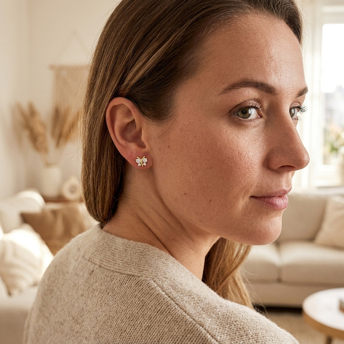 Ohrstecker Schmetterling mit 4 Zirkonia – 375er Gold, 6 × 6 mm – am Ohr getragen, natürliche Lifestyle-Aufnahme