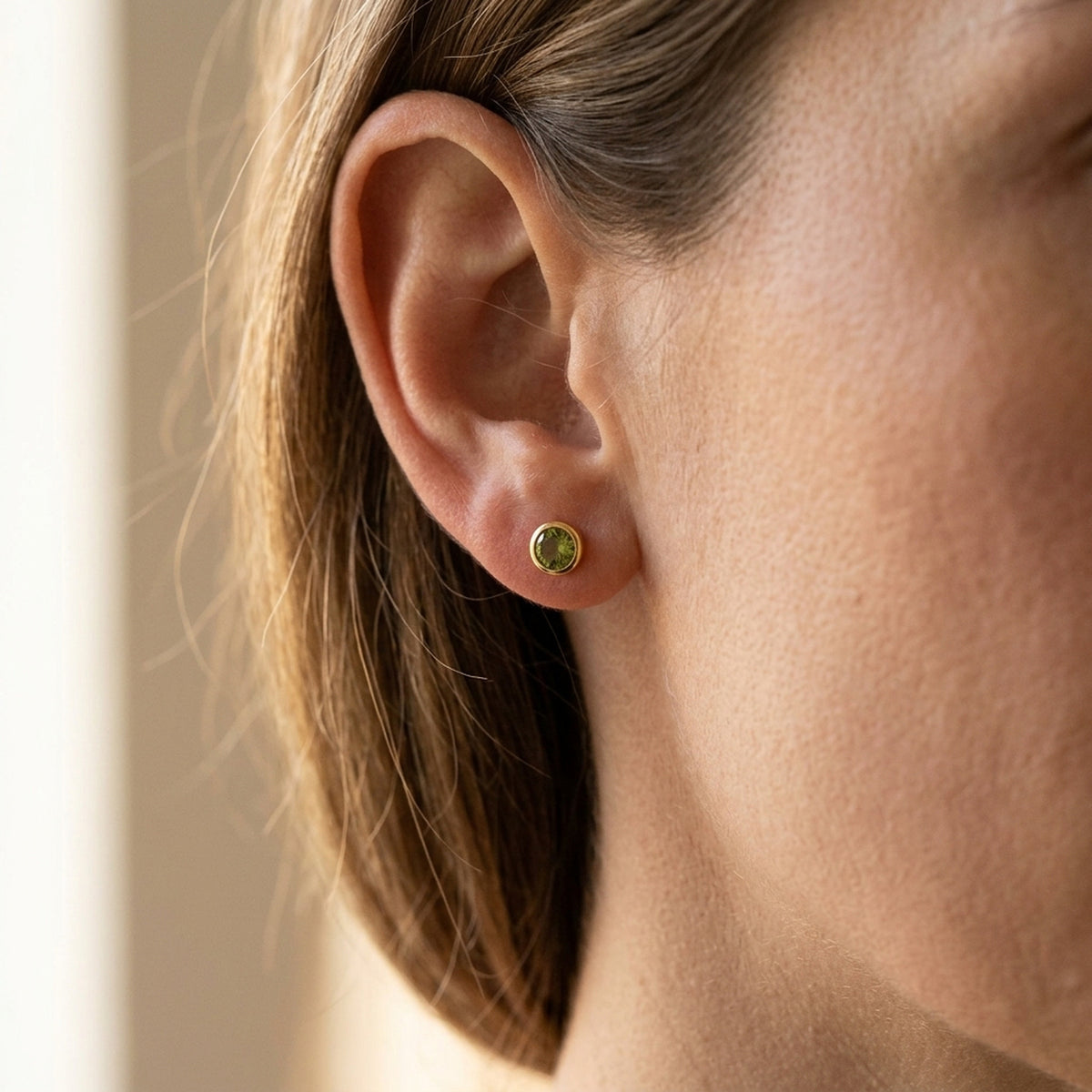 Ohrstecker mit Zirkonia olivgrün – 375er Gold, 4,5 mm – am Ohr getragen, zweite Lifestyle-Aufnahme in anderer Perspektive