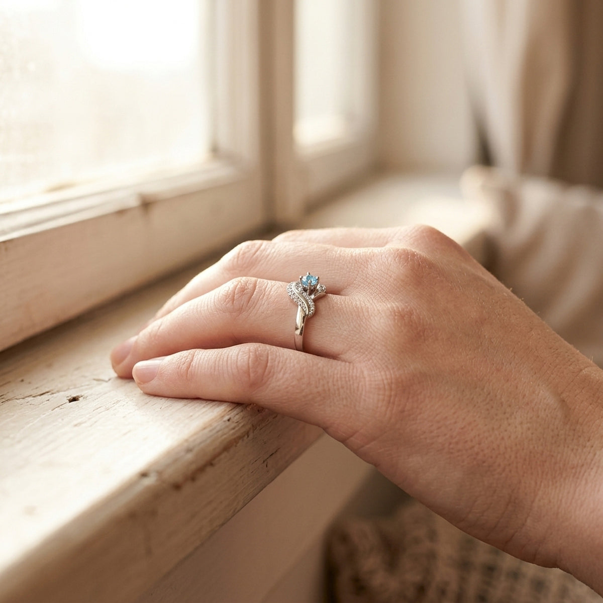 Ring mit aqua- und weißen Zirkonia glänzend rhodiniert – 925er Silber, 10 mm – an der Hand getragen, zweite Lifestyle-Aufnahme in anderer Perspektive
