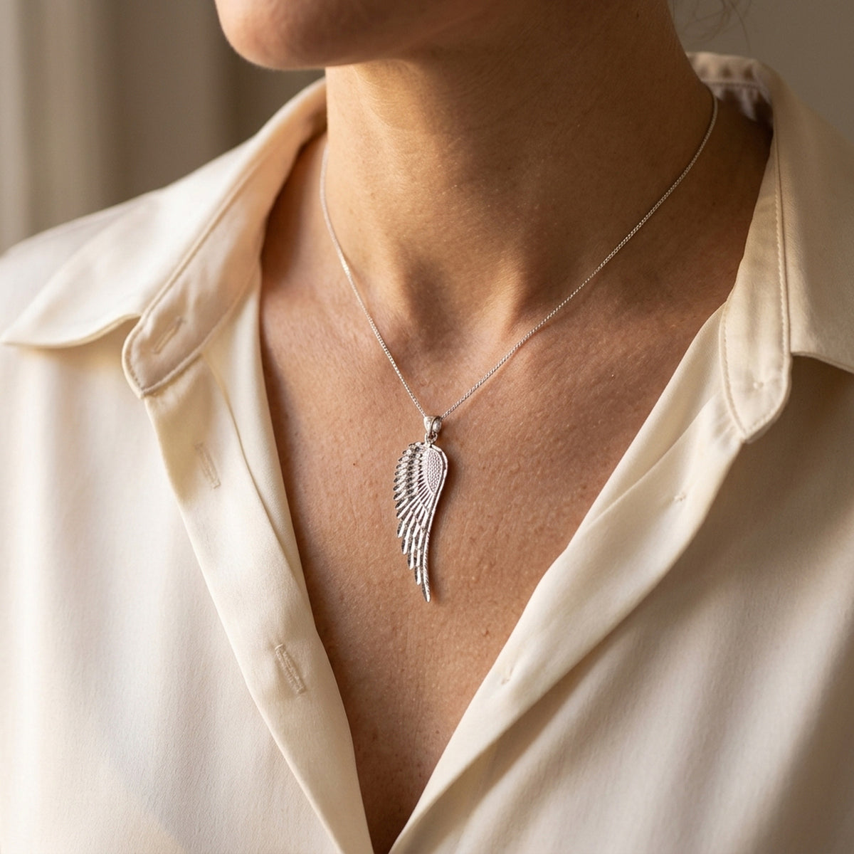 Anhänger Flügel diamantiert rhodiniert – 925er Silber, 37 × 12 mm – an einer feinen Kette getragen, natürliche Lifestyle-Aufnahme