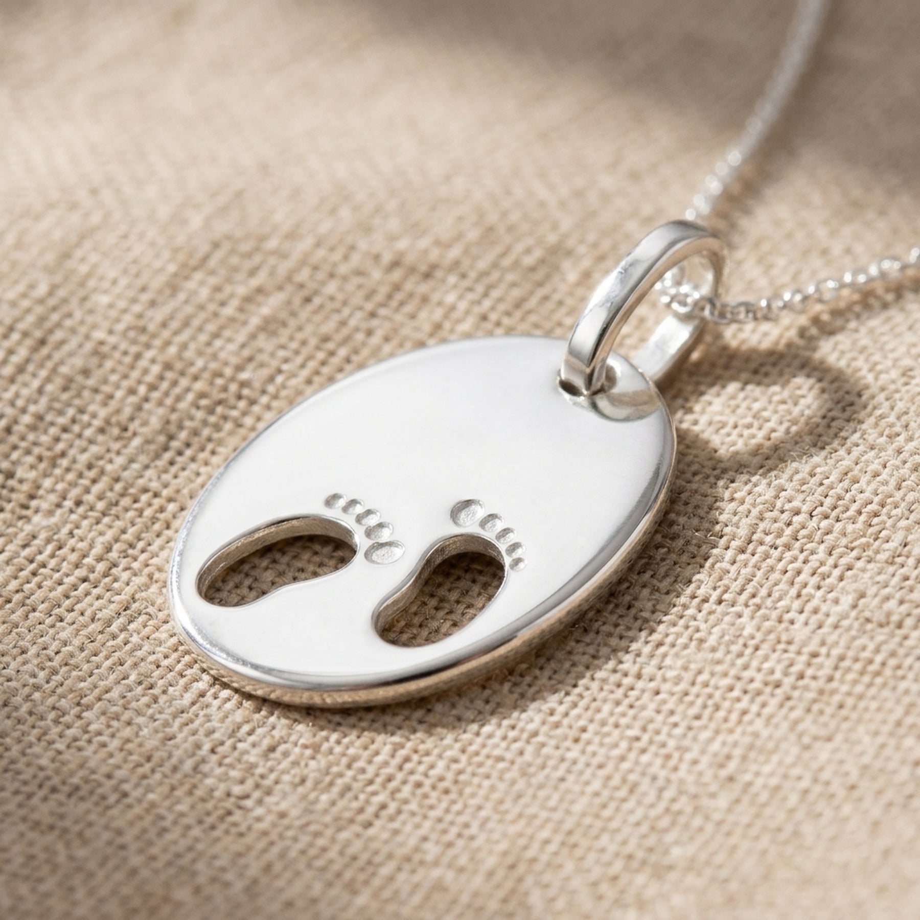 Anhänger Gravuranhänger zur Geburt kleine Füße – 925er Silber, 21 × 17 mm – Detailansicht des Anhängers vor neutralem Hintergrund