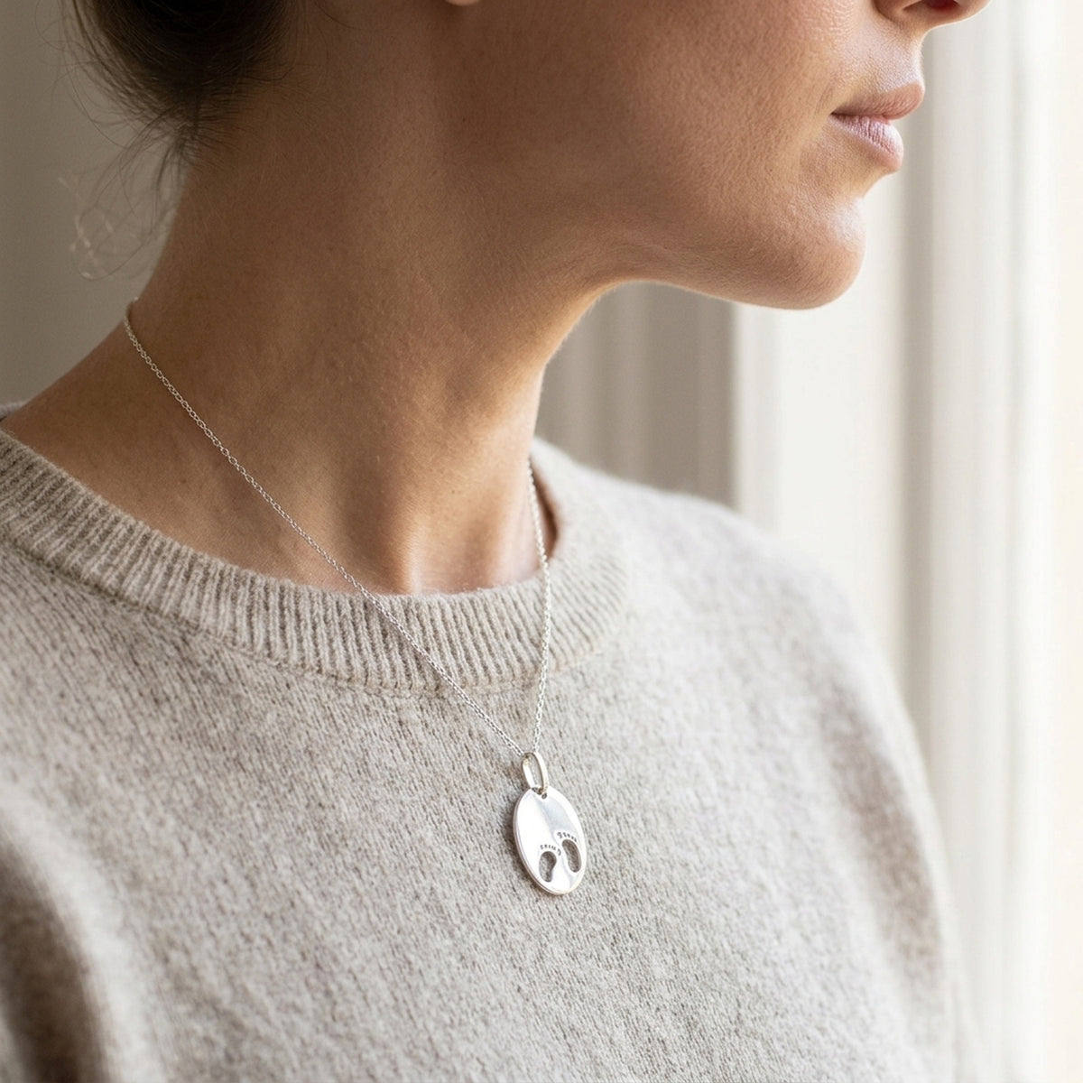 Anhänger Gravuranhänger zur Geburt kleine Füße – 925er Silber, 21 × 17 mm – an einer feinen Kette getragen, zweite Lifestyle-Aufnahme in anderer Perspektive