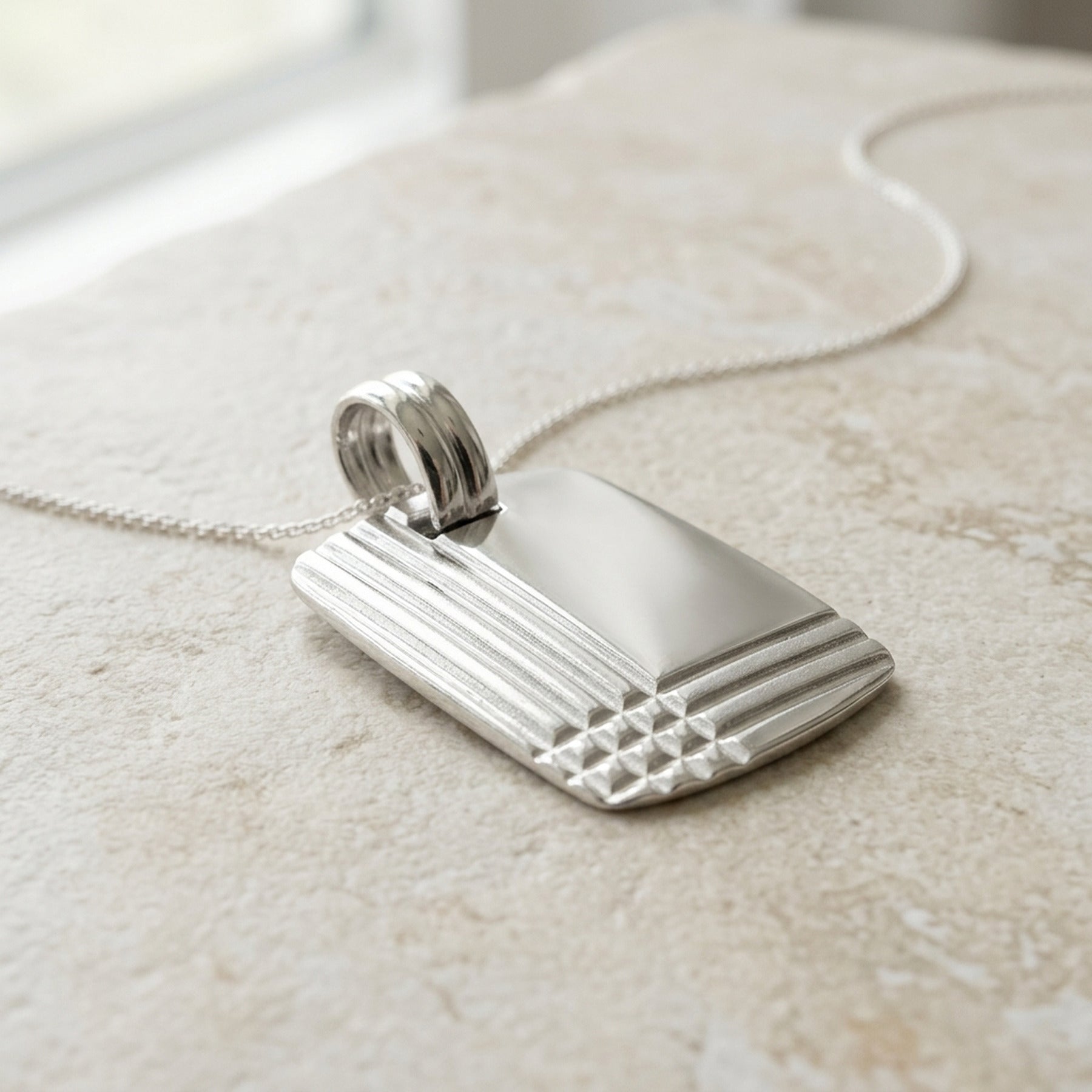 Anhänger Gravurplatte mit geprägtem Muster glänzend – 925er Silber, 24 × 17 mm – Detailansicht des Anhängers vor neutralem Hintergrund