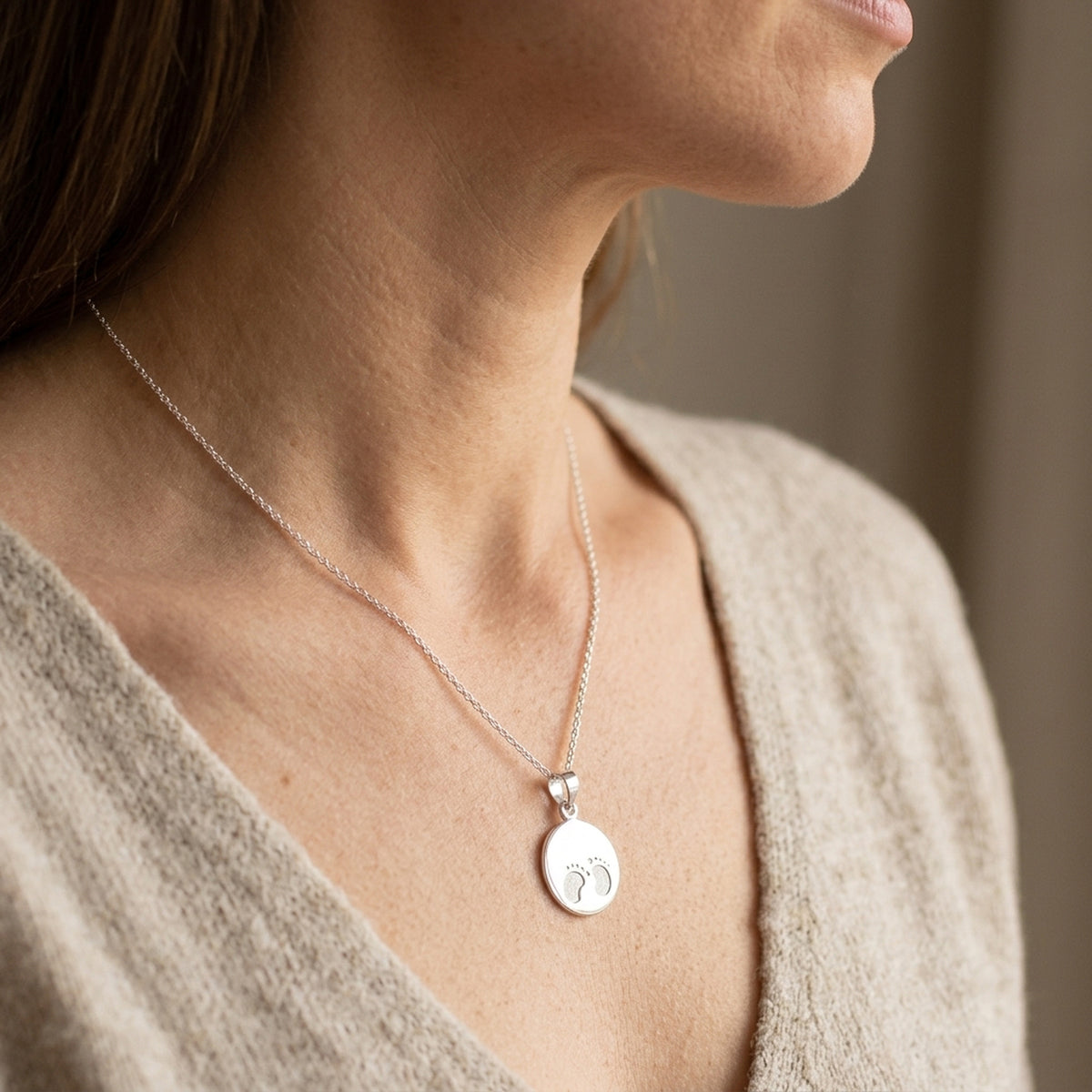 Anhänger kleine Füße glänzend – 925er Silber, 13 mm – an einer feinen Kette getragen, zweite Lifestyle-Aufnahme in anderer Perspektive