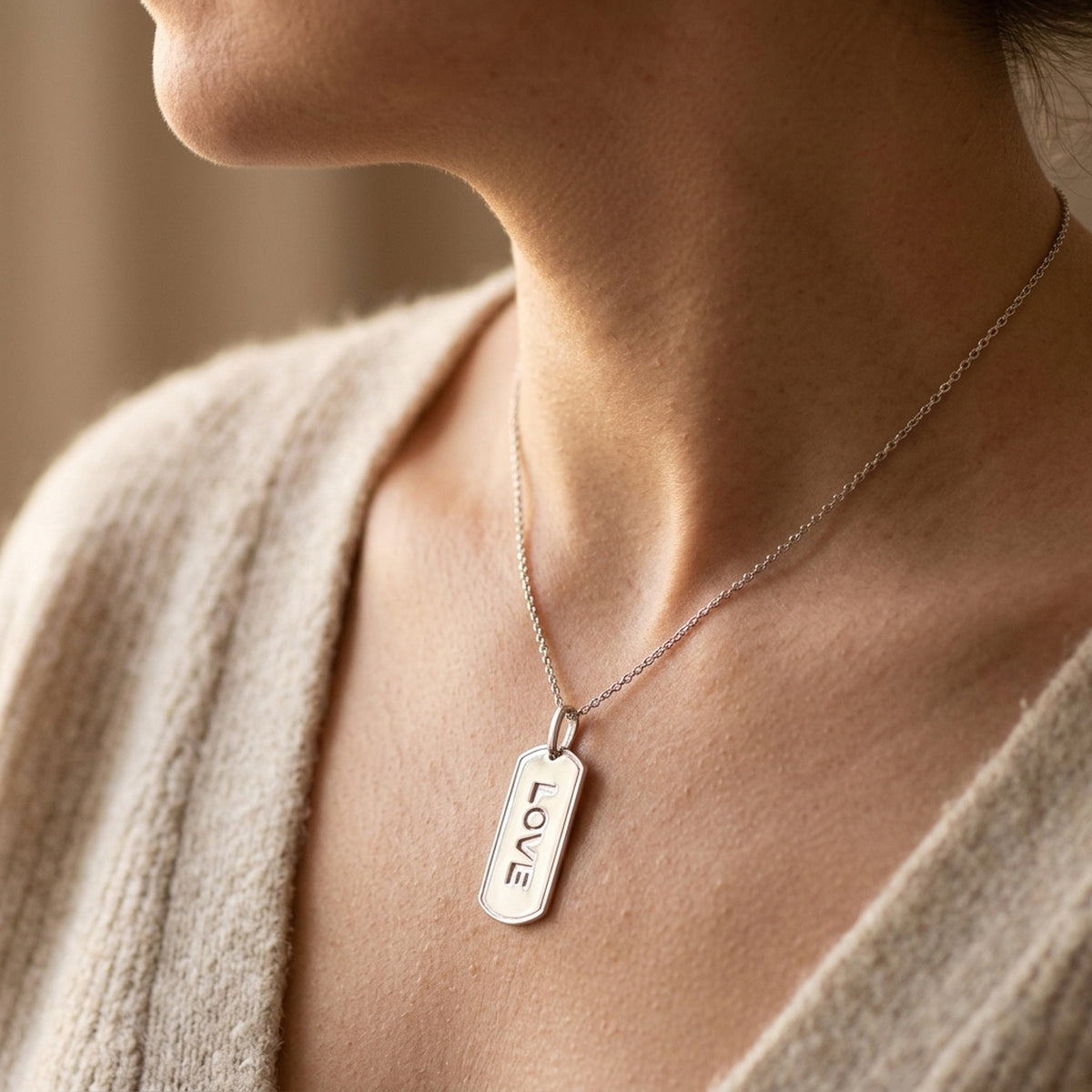 Anhänger LOVE rhodiniert – 925er Silber, 32 × 16 mm – an einer feinen Kette getragen, zweite Lifestyle-Aufnahme in anderer Perspektive