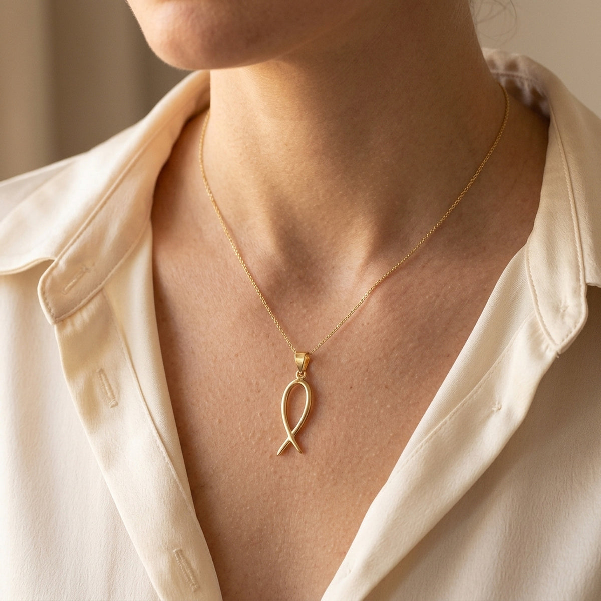 Anhänger Religiöses Symbol Jesus-Fisch glänzend – 375er Gold, 20 × 7 mm – an einer feinen Kette getragen, natürliche Lifestyle-Aufnahme