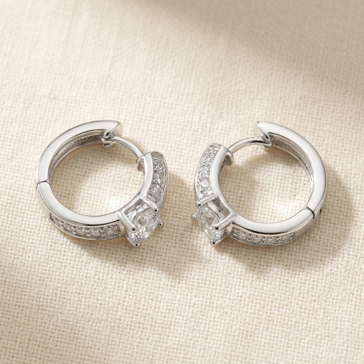 Creolen mit vielen Zirkonia, glänzend rhodiniert – 925er Silber, 15 × 4 mm – Detailansicht des Ohrschmucks vor neutralem Hintergrund
