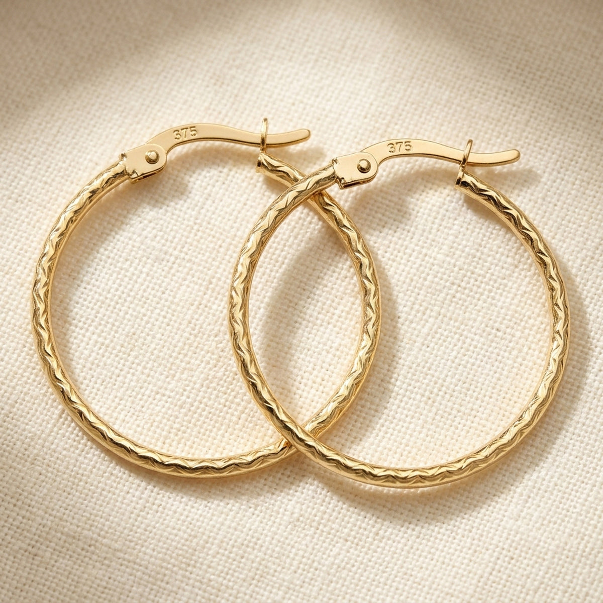 Creolen Bügelverschluss Muster glänzend diamantiert – 375er Gold, 23 × 1,5 mm – Detailansicht des Ohrschmucks vor neutralem Hintergrund