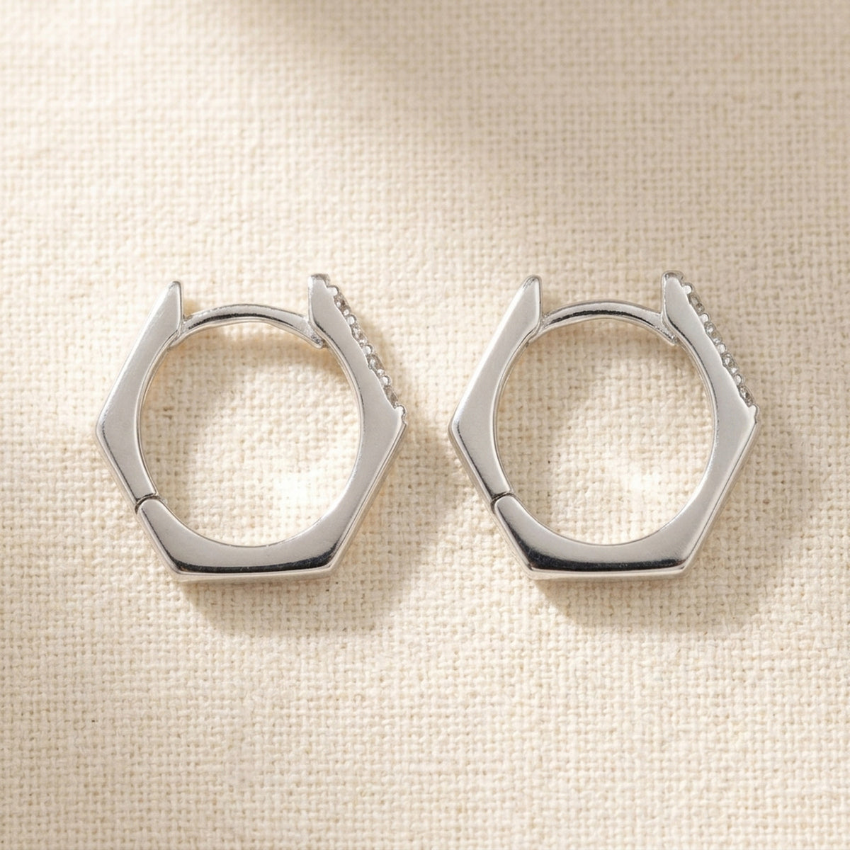 Sechseckige Creolen mit 4 weißen Zirkonia – 925er Silber, 15 × 14 × 1,5 mm – Detailansicht des Ohrschmucks vor neutralem Hintergrund