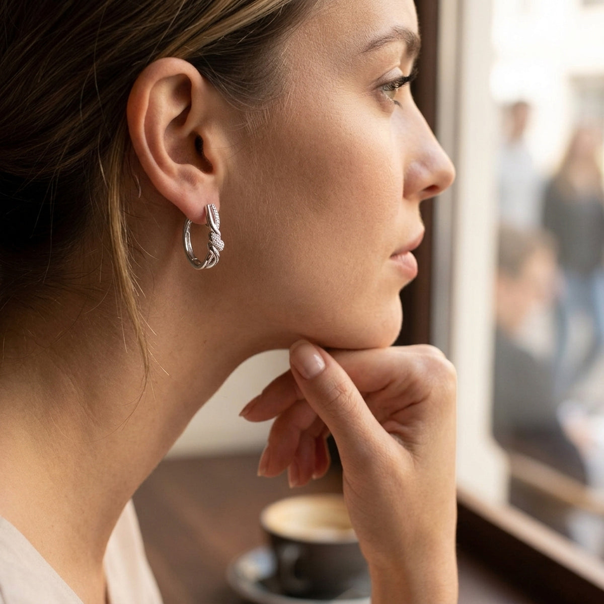 Überkreuzte Creolen mit Zirkonia, glänzend – 925er Silber, 17 × 4 mm – am Ohr getragen, zweite Lifestyle-Aufnahme in anderer Perspektive