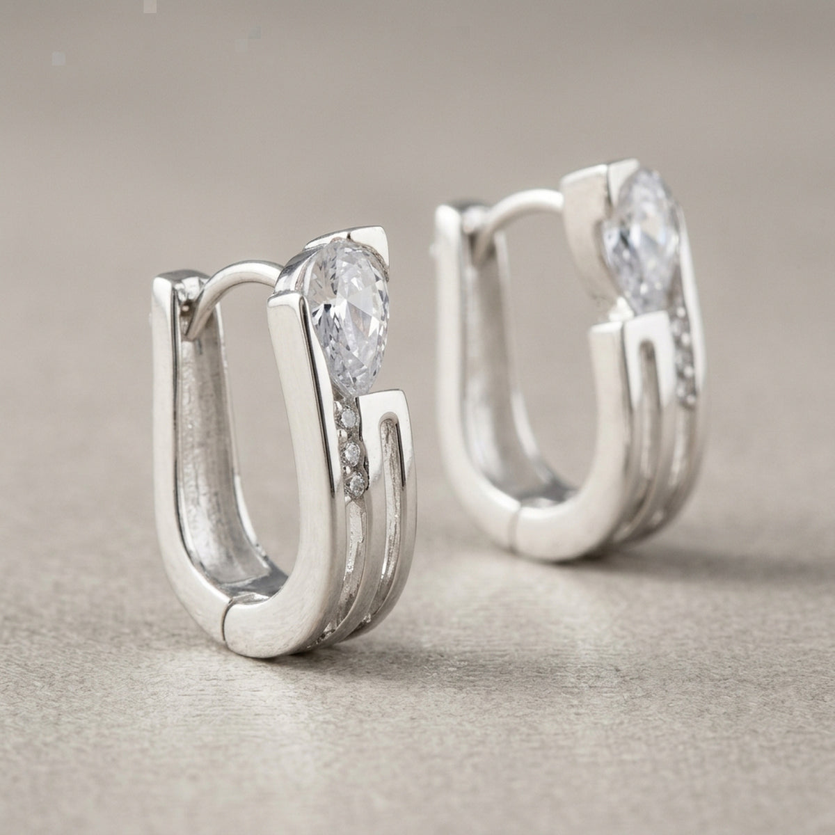 Creolen mit weißen Zirkonia – 925er Silber, 15 × 4,6 mm – Detailansicht des Ohrschmucks vor neutralem Hintergrund