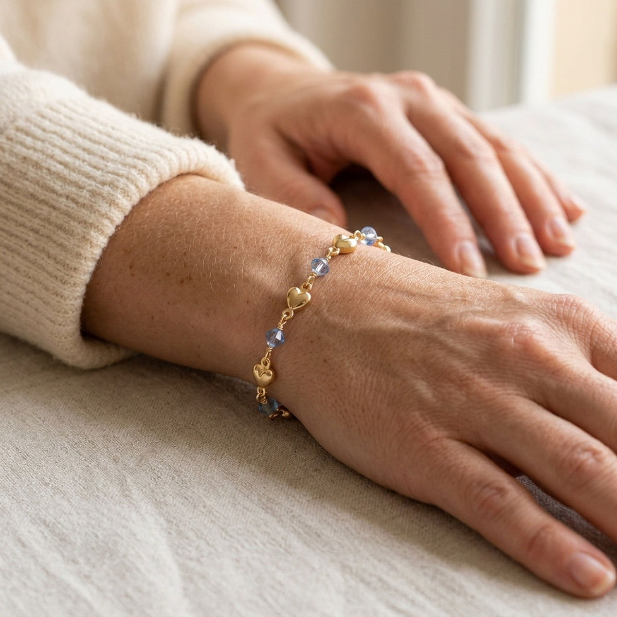 Armband mit Herz und blauer Glasperle – Doublé, 5 mm, 19 cm – am Handgelenk getragen, natürliche Lifestyle-Aufnahme