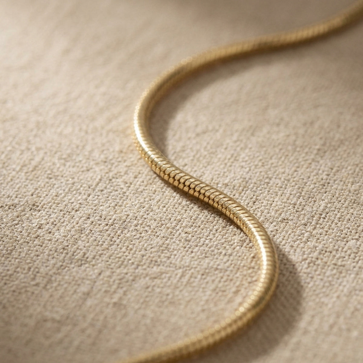 Kette Schlange 5-kant – 585er Gold, 0,7 mm – Detailansicht des Kettes vor neutralem Hintergrund