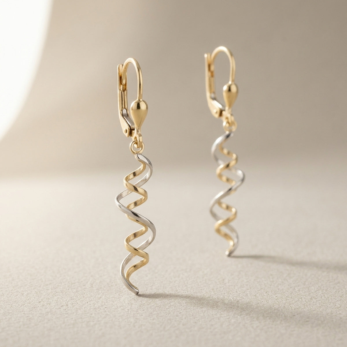 Ohrhänger mit zwei bicolor Spiralen – 375er Gelb- und Weißgold, 43 × 7 mm – Detailansicht des Ohrschmucks vor neutralem Hintergrund