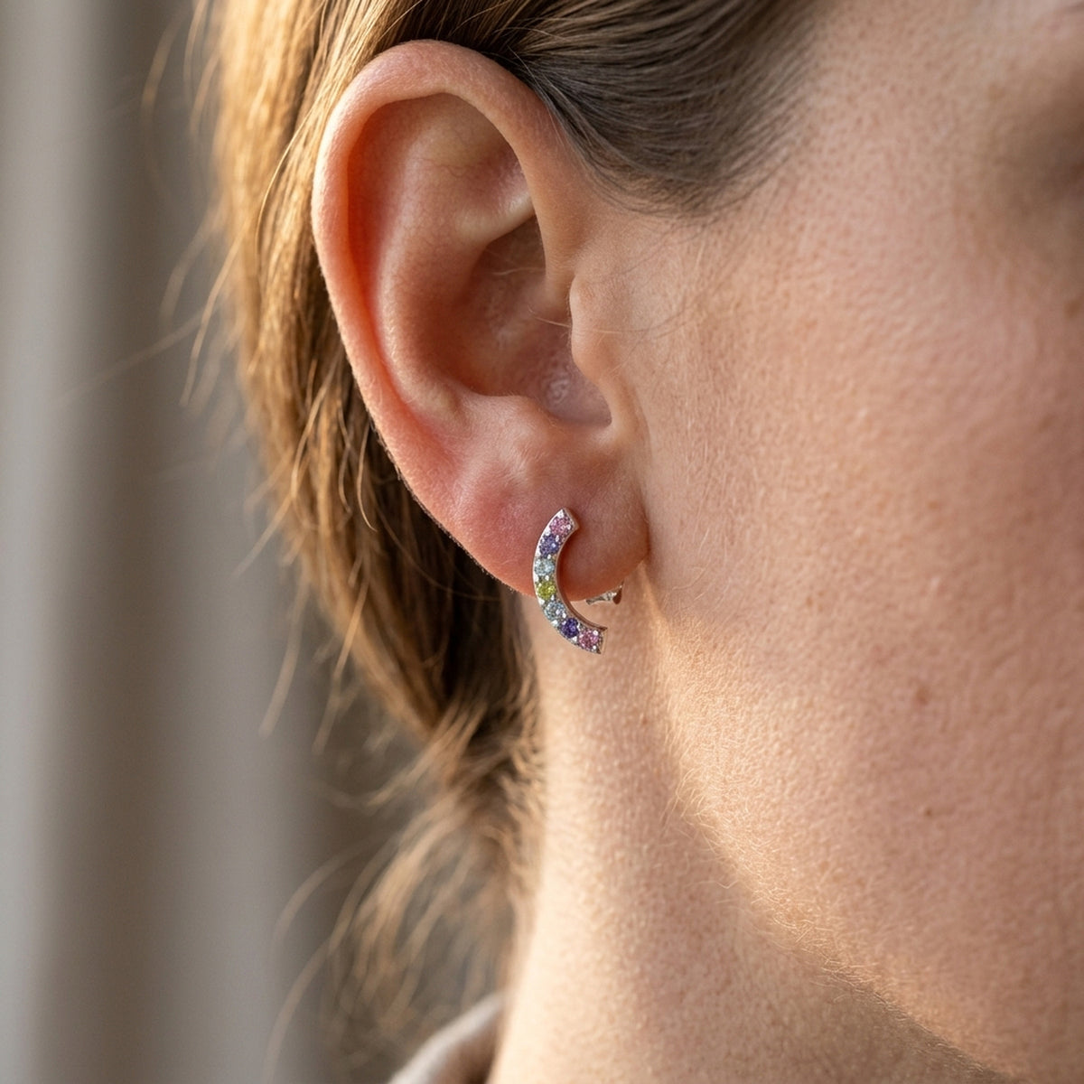 Ohrstecker Halbkreis mit farbigen Zirkonia – 925er Silber, 9 × 4 mm – am Ohr getragen, zweite Lifestyle-Aufnahme in anderer Perspektive