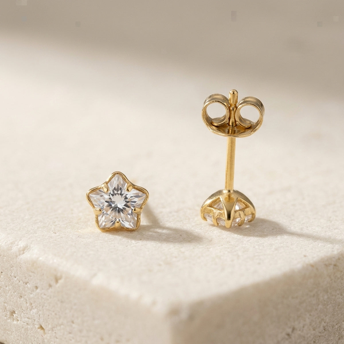 Ohrstecker mit Zirkonia in Blumenform – 375er Gold, 4 mm – Detailansicht des Ohrschmucks vor neutralem Hintergrund
