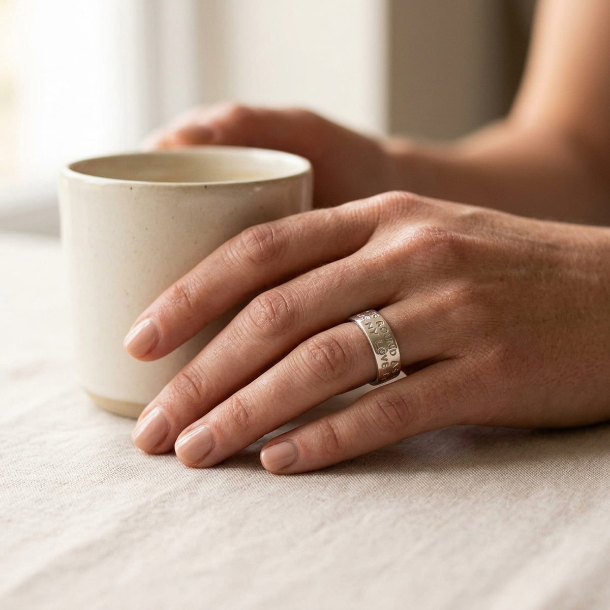 Ring mit Prägung LOVE HAS NO END – 925er Silber, 8 mm – an der Hand getragen, natürliche Lifestyle-Aufnahme